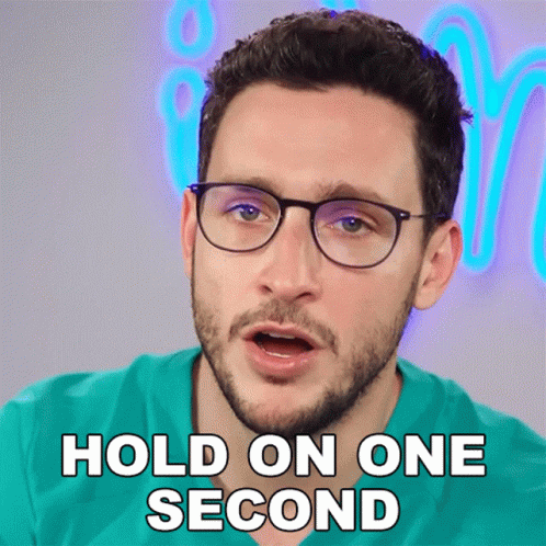 A Man With Glasses And A Beard Says " Hold On One Second " GIF