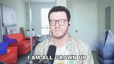 A Man With Glasses And A Beard Says I Am All Grown Up In Front Of A Microphone GIF