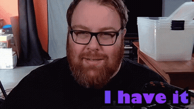 A Man With Glasses And A Beard Says " I Have It " In Purple Letters GIF