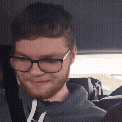 A Man With Glasses And A Beard Smiles For The Camera GIF
