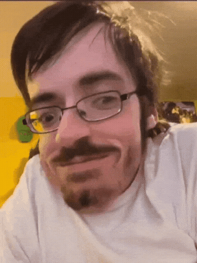 A Man With Glasses And A Beard Smiles For The Camera GIF