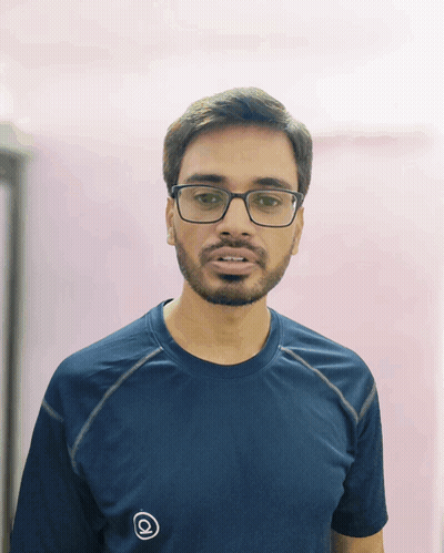 A Man With Glasses And A Beard Wears A Blue Shirt With The Letter Q On The Front GIF