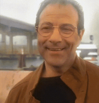 A Man With Glasses And A Brown Jacket Is Smiling GIF
