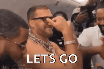 A Man With Glasses And A Chain Around His Neck Is Covering His Nose With His Hand And The Words `` Lets Go '' Are Visibl GIF