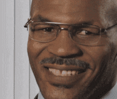 A Man With Glasses And A Mustache Is Smiling And Looking At The Camera GIF