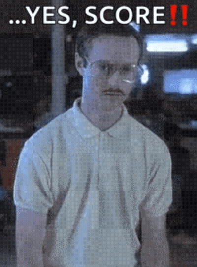 A Man With Glasses And A Mustache Is Standing In Front Of A Sign That Says Yes Score GIF