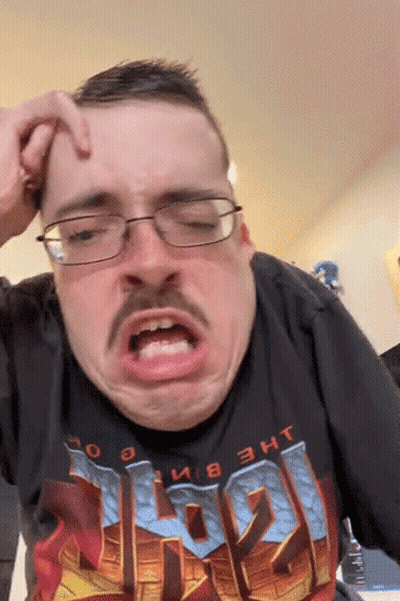 A Man With Glasses And A Mustache Is Wearing A Doom Shirt And Making A Funny Face GIF