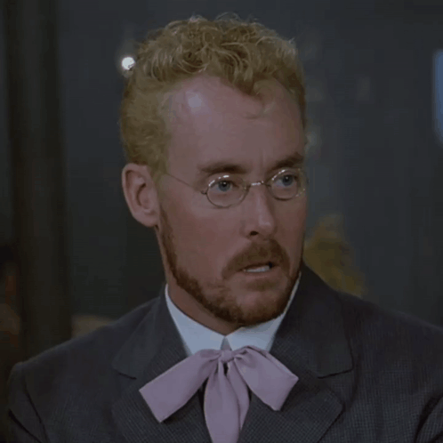 A Man With Glasses And A Pink Tie Looks Surprised GIF