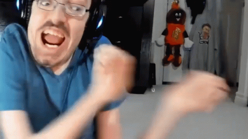 A Man With Glasses And A Reese 'S Candy Mascot Behind Him GIF