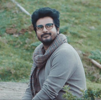 A Man With Glasses And A Scarf Around His Neck Smiles For The Camera GIF