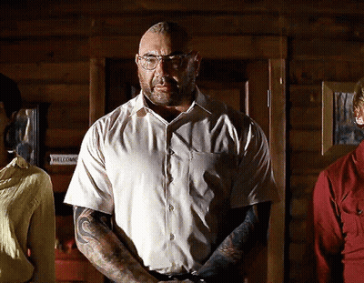 A Man With Glasses And A Tattoo On His Arm Stands In Front Of A Door That Says Welcome GIF