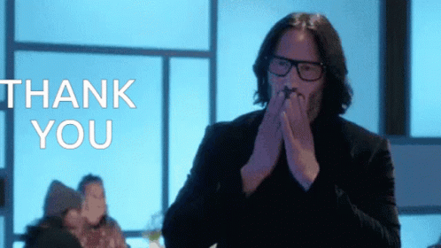 A Man With Glasses Is Covering His Mouth In Front Of A Thank You Sign GIF