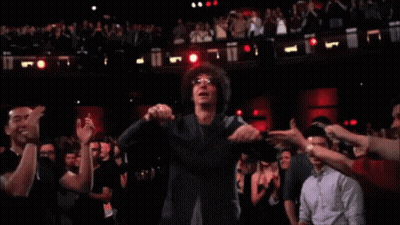 A Man With Glasses Is Dancing In Front Of A Crowd Of People GIF