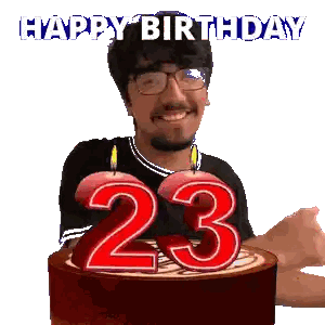 A Man With Glasses Is Holding A Cake With The Number 23 On It Sticker