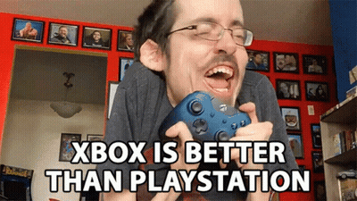 A Man With Glasses Is Holding A Video Game Controller With The Words Xbox Is Better Than Playstation Below Him GIF