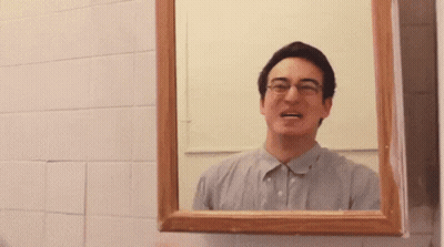 A Man With Glasses Is Looking At Himself In A Bathroom Mirror GIF