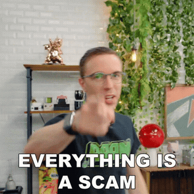 A Man With Glasses Is Pointing At The Camera With The Words Everything Is A Scam Behind Him GIF