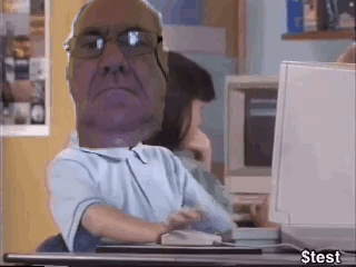 A Man With Glasses Is Sitting At A Desk With A Computer . GIF