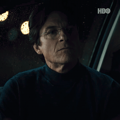 A Man With Glasses Is Sitting In A Dark Room With A Hbo Logo In The Corner GIF