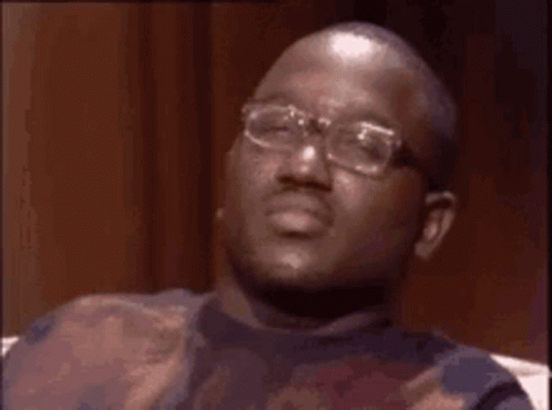 A Man With Glasses Is Sitting On A Couch And Making A Funny Face . GIF