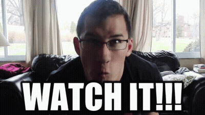 A Man With Glasses Is Sitting On A Couch With The Words Watch It GIF