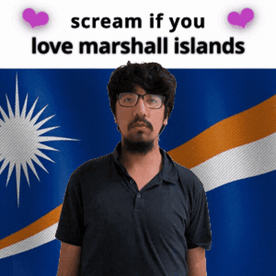 A Man With Glasses Is Standing In Front Of A Flag That Says " Scream If You Love Marshall Islands " GIF