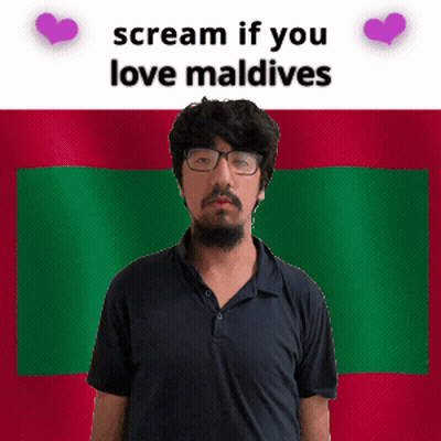A Man With Glasses Is Standing In Front Of A Maldives Flag GIF