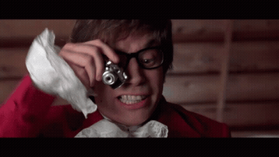 A Man With Glasses Is Taking A Picture With A Small Camera GIF