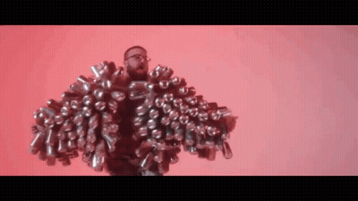 A Man With Glasses Is Wearing A Jacket Made Out Of Cans . GIF