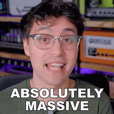 A Man With Glasses Says " Absolutely Massive " In Front Of An Orange Amplifier GIF