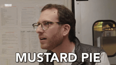 A Man With Glasses Says Mustard Pie In Front Of A Menu Board GIF