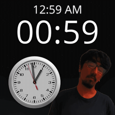 A Man With Glasses Stands In Front Of A Clock That Reads 12:59 Am GIF