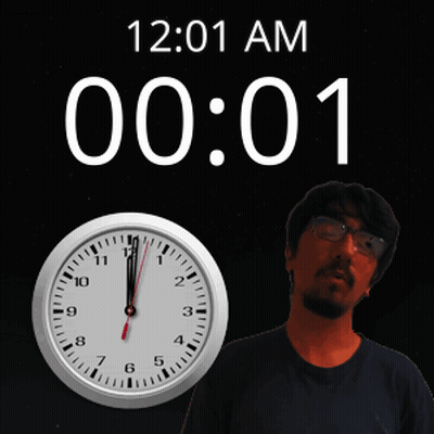 A Man With Glasses Stands In Front Of A Clock That Says 12:01 Am GIF