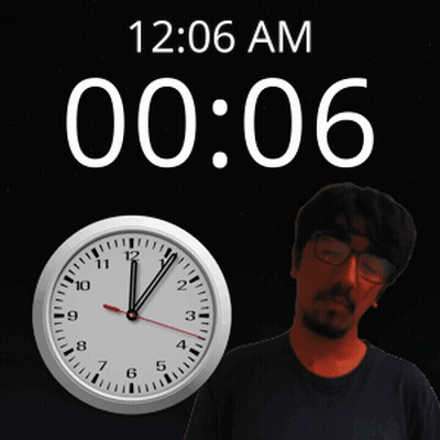 A Man With Glasses Stands In Front Of A Clock That Says 12:06 Am GIF