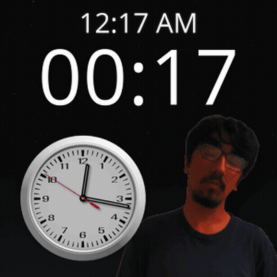 A Man With Glasses Stands In Front Of A Clock That Says 12 17 Am 00 17 GIF