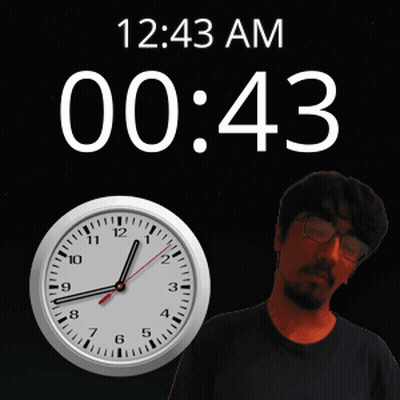 A Man With Glasses Stands In Front Of A Clock That Says 12 43 Am GIF
