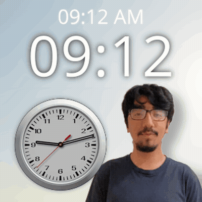 A Man With Glasses Stands In Front Of A Clock That Says 9:12 Am GIF