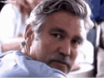 A Man With Gray Hair And A Beard Is Looking Over His Shoulder GIF