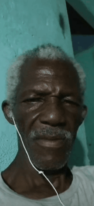 A Man With Gray Hair And A Beard Wearing Earbuds GIF