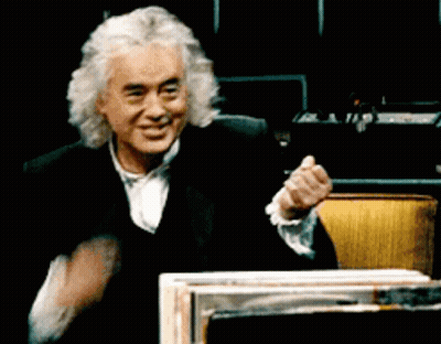 A Man With Gray Hair And A Black Suit Is Smiling And Clapping His Hands GIF