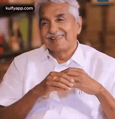 A Man With Gray Hair And A Mustache Is Smiling And Talking To Someone While Wearing A White Shirt And Tie . GIF