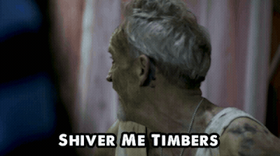 A Man With Gray Hair And A White Tank Top Says Shiver Me Timbers GIF