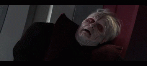 A Man With Gray Hair And Red Eyes Is Laying On A Bed GIF