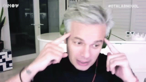 A Man With Gray Hair Is Making A Funny Face With His Hands On His Forehead . GIF