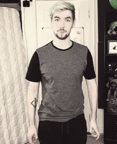 A Man With Green Hair And A Beard Is Standing In Front Of A Mattress . GIF