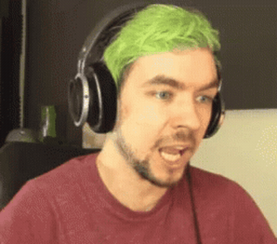 A Man With Green Hair And Headphones On Is Making A Funny Face . GIF