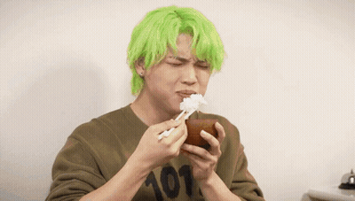A Man With Green Hair Is Eating Rice From A Bowl Next To Another Man GIF