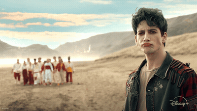 A Man With Green Hair Is Standing In Front Of A Group Of People Wearing A Disney + Jacket GIF