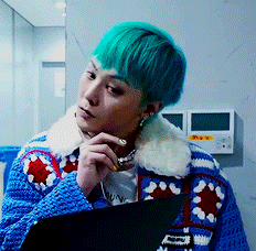 A Man With Green Hair Is Wearing A Blue Sweater With A White Collar GIF