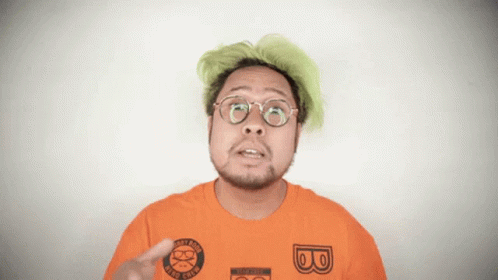 A Man With Green Hair Is Wearing An Orange Shirt With The Letter B On The Front GIF